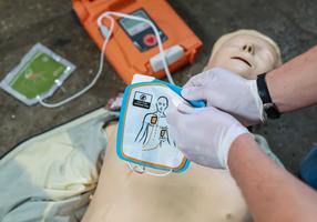 Erste Hilfe Übung mit Defibrillator an einer Puppe