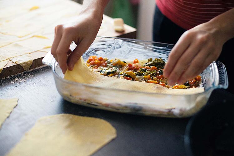 Eine Frau bereitet eine Gemüse-Lasagne zu.