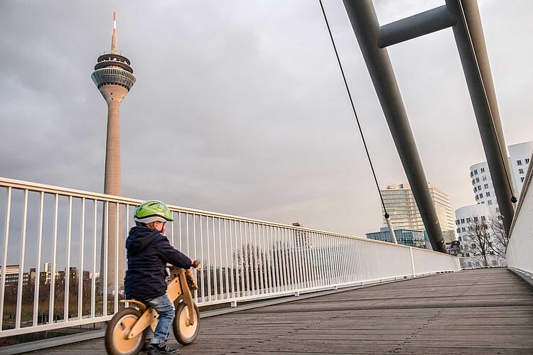 Kleiner Junge mit Laufrad auf einer Brücke