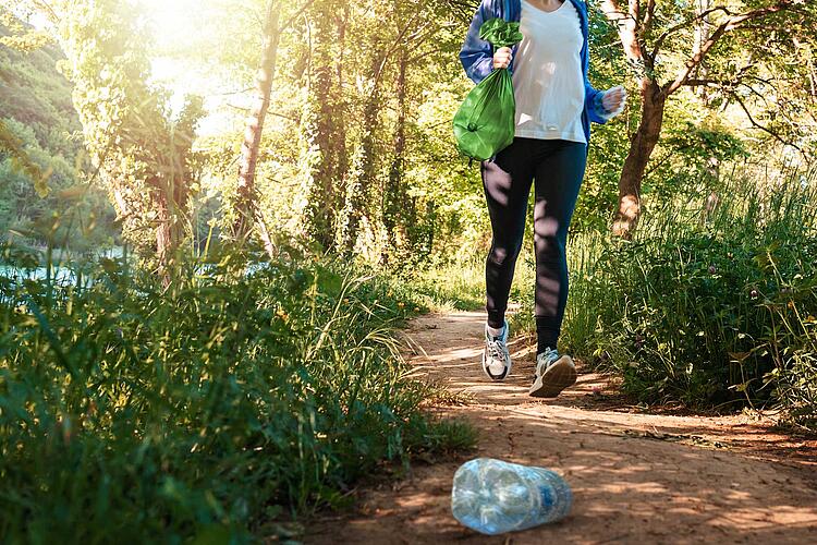 Plogging: Frau sammelt Müll beim Joggen