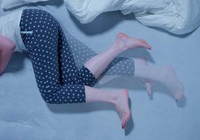 Frau mit RLS Restless Legs Syndrom liegt im Bett Frau mit RLS Restless Legs Syndrom liegt im Bett