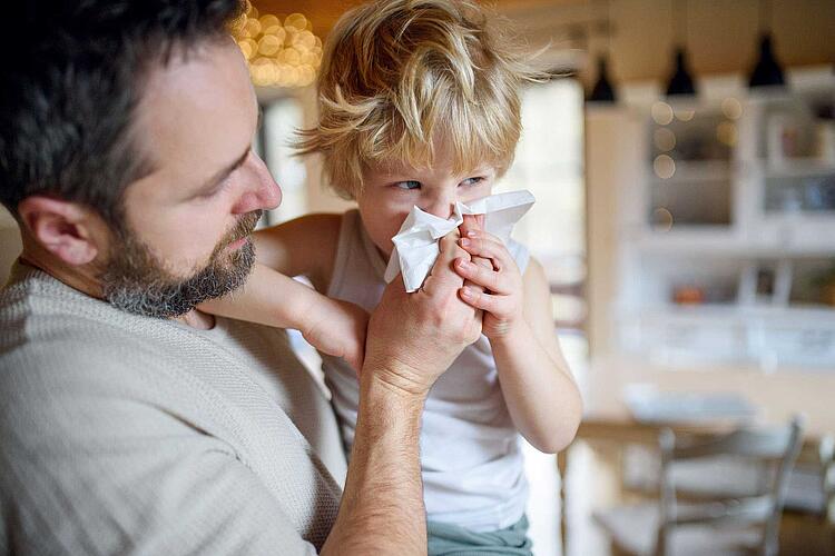 Vater putzt seinem Sohn die Nase.
