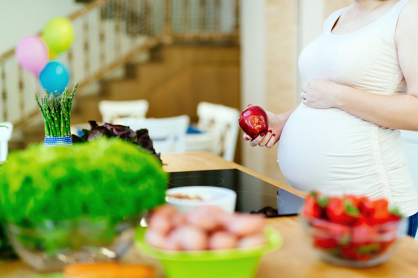 Eine Schwangere bereitet in der Küche gesundes Essen zu.