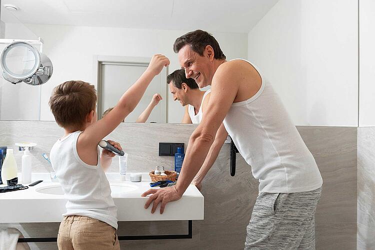 Kleiner Junge ist mit dem Vater im Bad und benutzt dessen Deodorant.