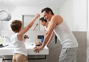 Kleiner Junge ist mit dem Vater im Bad und benutzt dessen Deodorant.