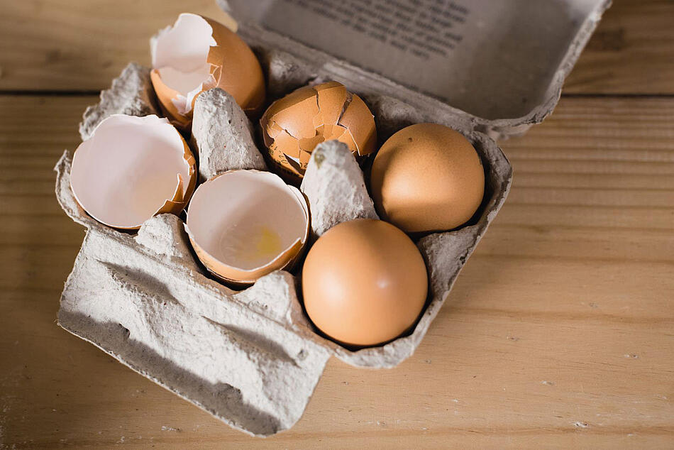 Zwei Eier und vier Eierschalen in einem Eierkarton.