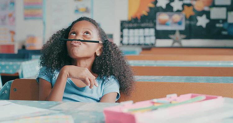 Mädchen spielt in der Schule gelangweilt mit einem Bleistift