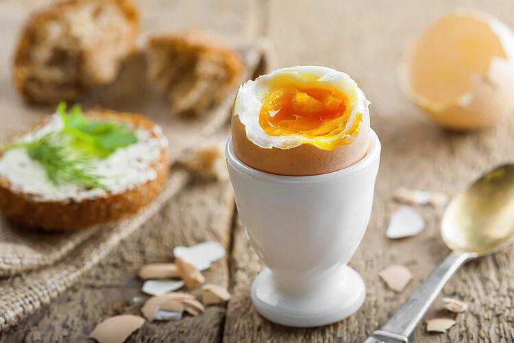 Geköpftes Frühstücksei in einem Eierbecher auf dem Frühstückstisch
