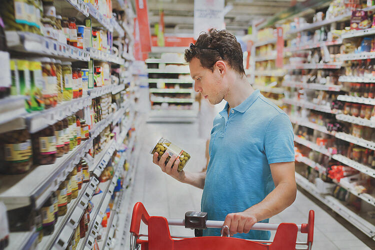 Mann prüft beim Einkaufen die Zutatenliste einses Produktes