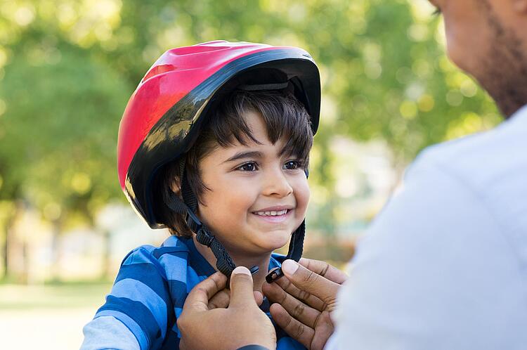 Vater setzt kleinem Sohn Fahrradhelm auf