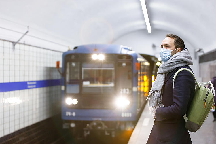 Mann mit Mundschutz wartet auf einem Bahnsteig auf den einfahrenden Zug. - Bildnachweis: © stock.adobe.com / DimaBerlin Mann mit Mundschutz wartet auf einem Bahnsteig auf den einfahrenden Zug.