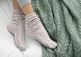Schlafen mit Socken  – Frau liegt mit Wollsocken im Bett