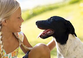 Mädchen und Hund schauen sich an.