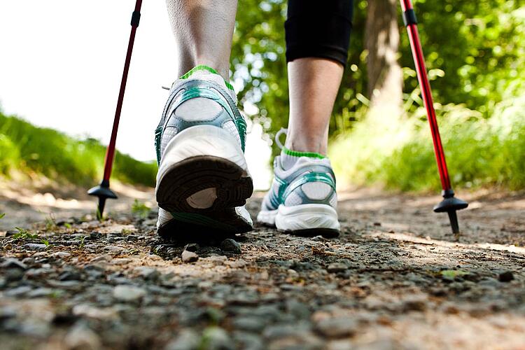 Füße einer Frau und Nordic Walking Stöcke.