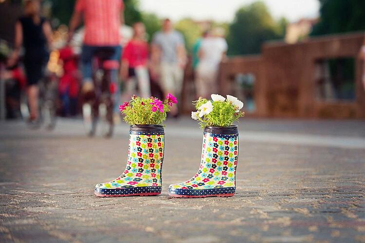 Mit Blumen bepflanzte Gummistiefel stehen in der Stadt