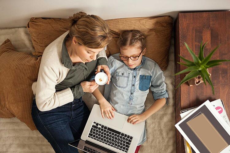 Junges Mädchen am Laptop und die Mutter schaut zu