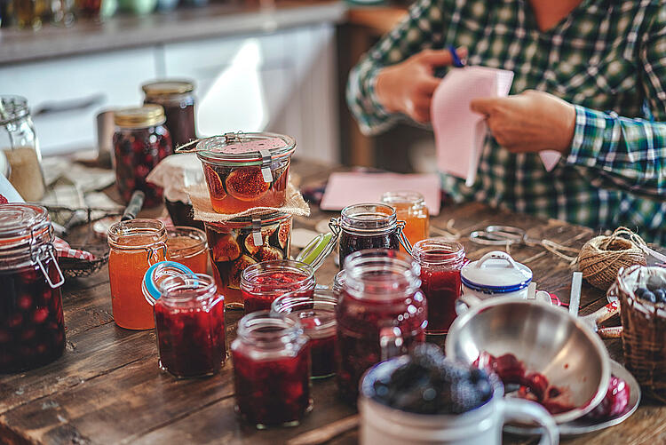 Ein Tisch voll mit frisch gekochter Marmelade in Gläsern.