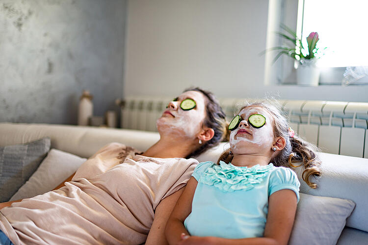 Mutter und Tochter entspannen mit Gesichtsmaske und Gurkenscheiben auf den Augen