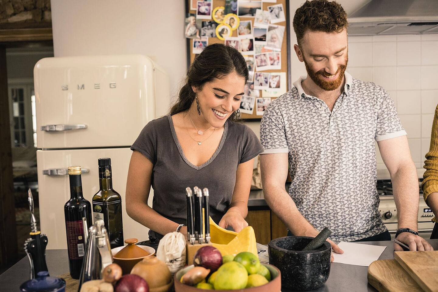 Paar steht in der Küche und schaut auf ein Rezept.