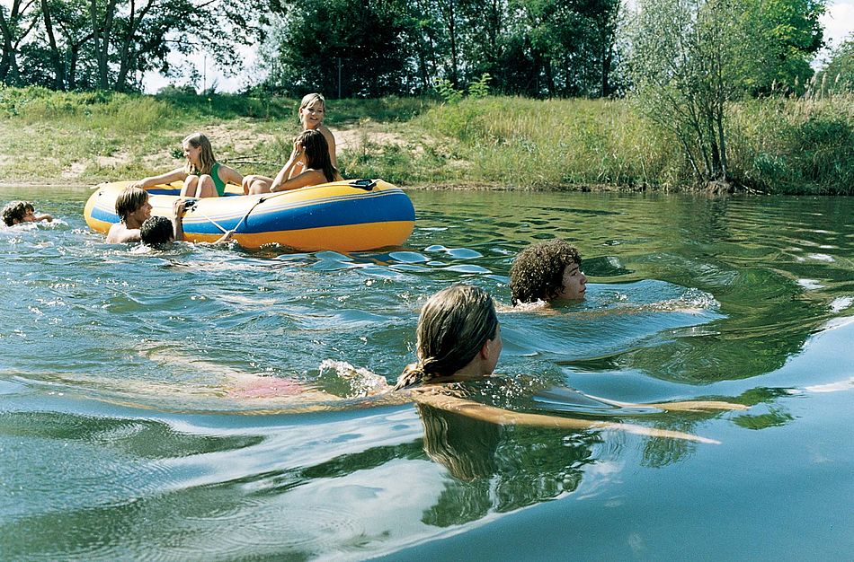 Gruppe junger Menschen in einem See beim Schwimmen und Schlauchbootfahren. - Bildnachweis: © wdv / Michael Völler Gruppe junger Menschen in einem See beim Schwimmen und Schlauchbootfahren.