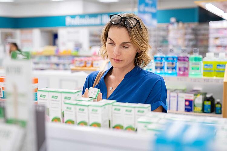 Frau liest die Angaben auf der Verpackung eines Medikamentes