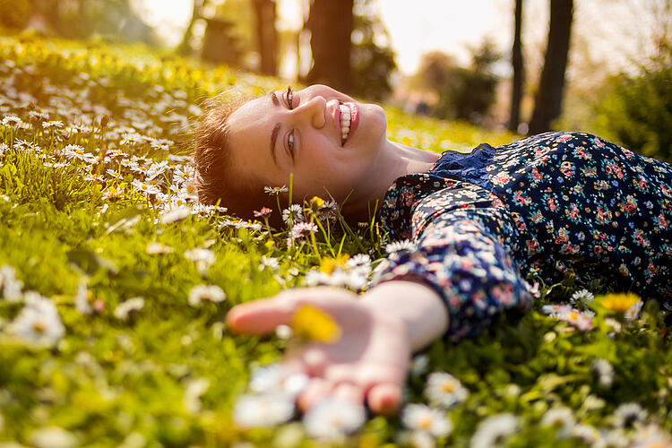Junge Frau liegt auf einer Blumenwiese