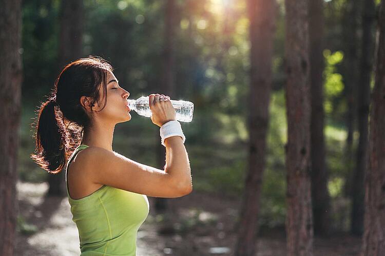 Frau trinkt Wasser aus einer Flasche