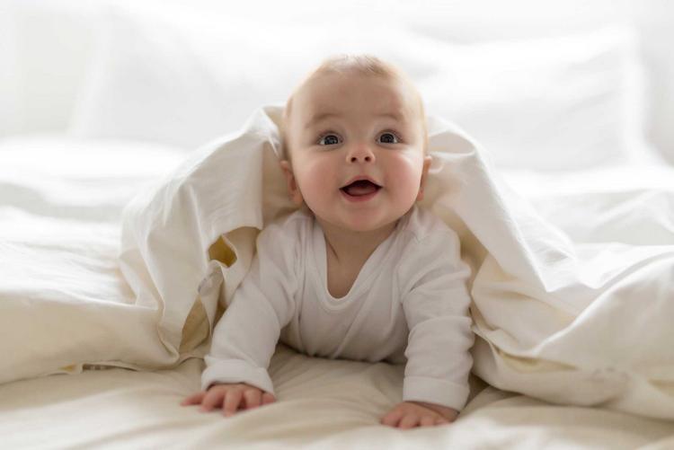 Baby liegt auf dem Bauch und stuetzt sich mit den Armen ab