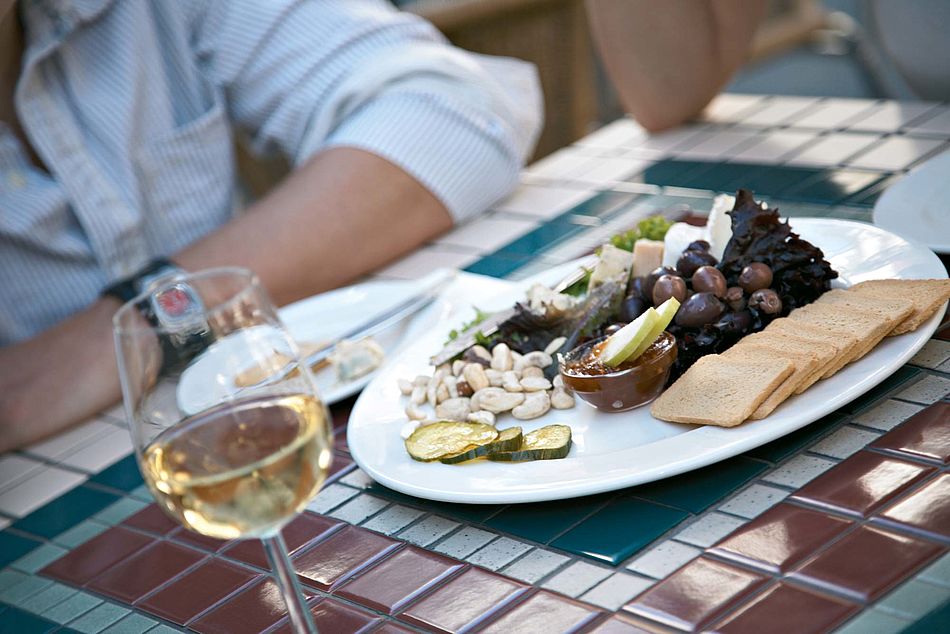 Eine Vorspeisenplatte und ein Glas Weißwein stehen auf einem Tisch. - Bildnachweis: © wdv / Jan Lauer Eine Vorspeisenplatte und ein Glas Weißwein stehen auf einem Tisch.