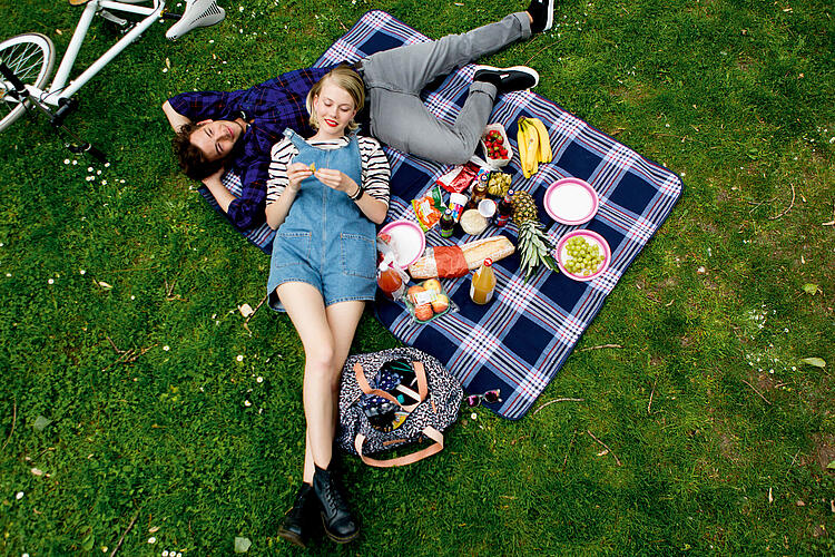 Junges Paar liegt auf einer Picknickdecke.