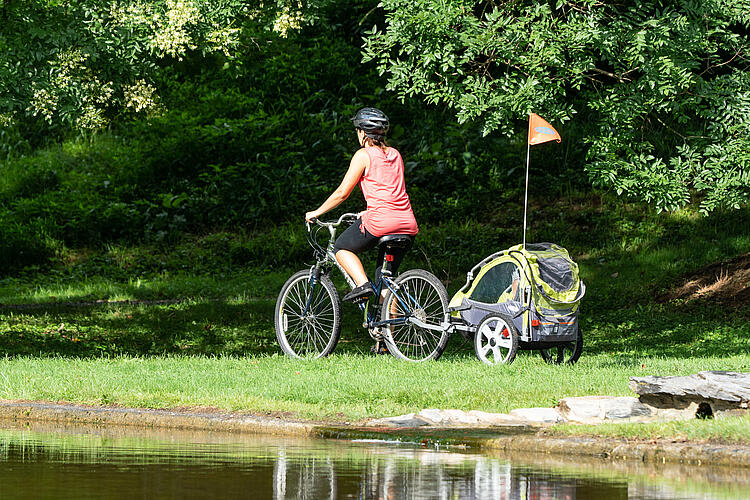 Frau fährt Fahrrad mit Anhänger für Kinder.