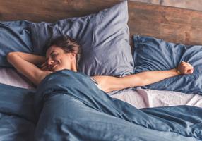 Frau streckt sich lächelnd im Bett
