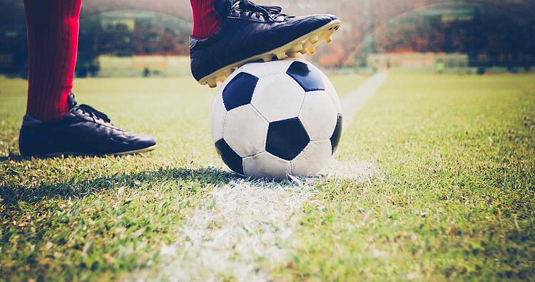 Fuß mit Fußballschuhen auf einem Fußball