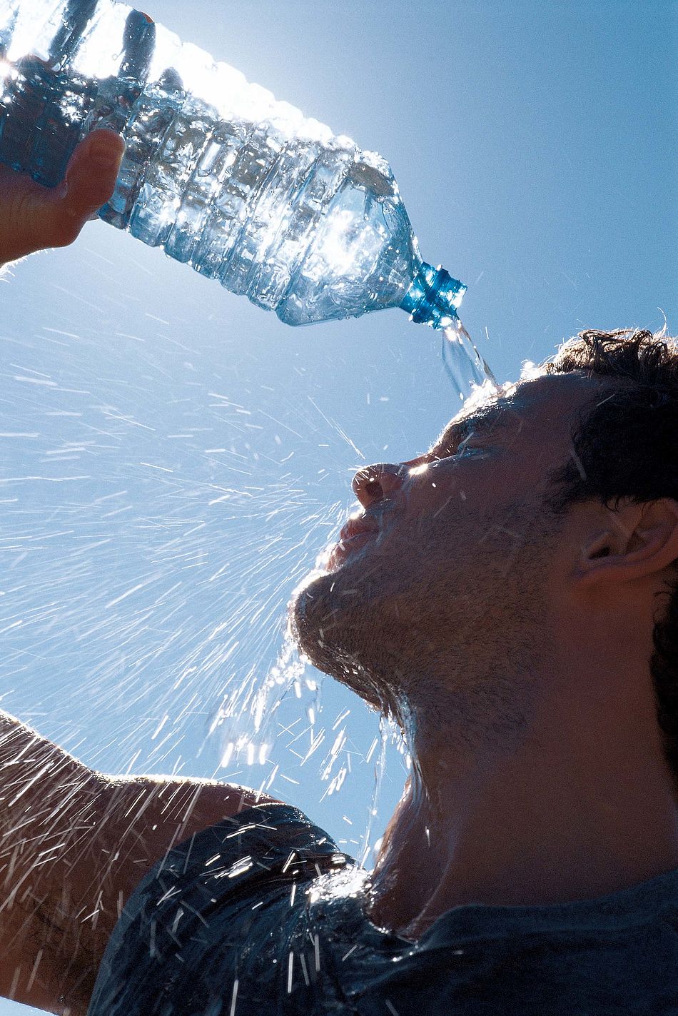 Mann gießt sich zur Abkühlung Wasser aus einer Flasche über das Gesicht. - Bildnachweis: © wdv / Jan Lauer Mann gießt sich zur Abkühlung Wasser aus einer Flasche über das Gesicht.