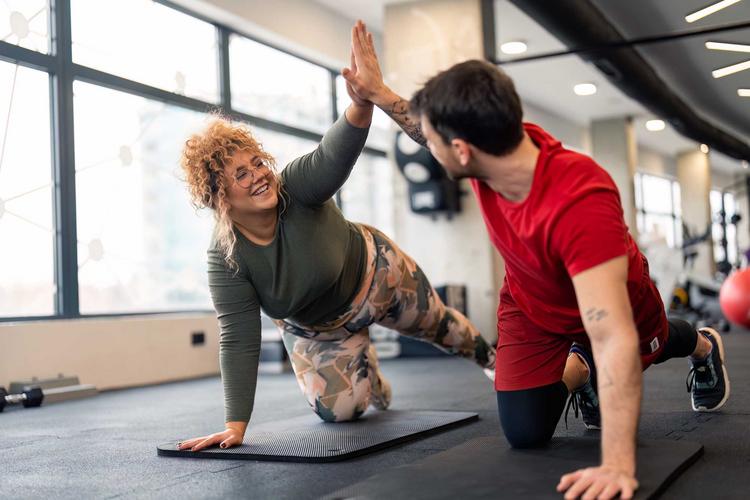 Bildnachweis: © stock.adobe.com / Dorde Personal Trainer gibt einer jungen Frau ein High Five nach dem Workout