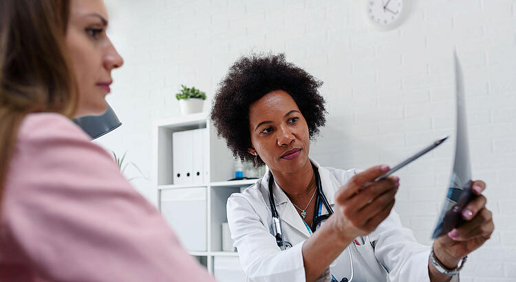 Ärztin erklärt einer Patientin ein Röntgenbild.