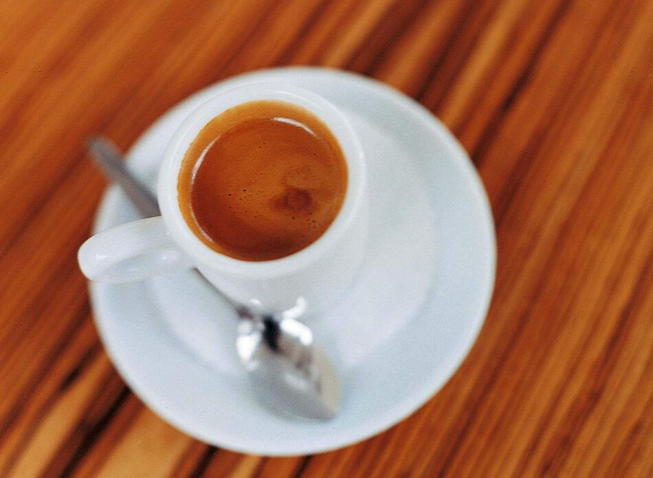 Eine Tasse Espresso mit einem Löffel auf dem Unterteller.