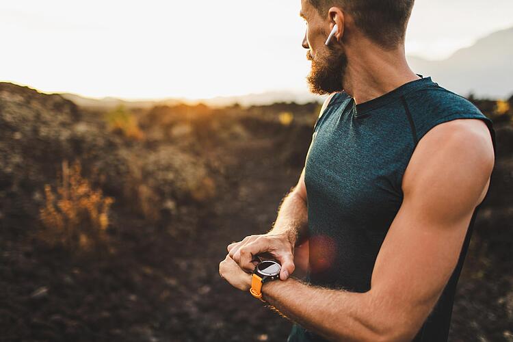 Mann schaut beim Joggen auf seine Smartwatch