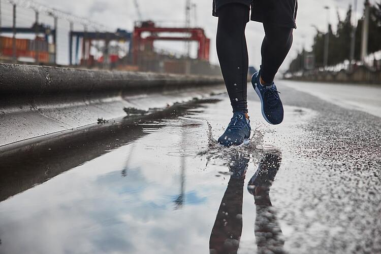 Mann joggt durch eine Pfütze