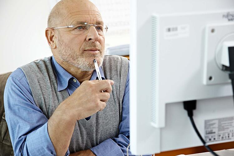 Mann schaut auf einen Computerbildschirm.