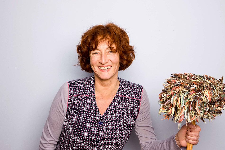 Lachende Frau in einer Kittelschürze hält einen Wischmop in der Hand. - Bildnachweis: © wdv / Michael Völler Lachende Frau in einer Kittelschürze hält einen Wischmop in der Hand.