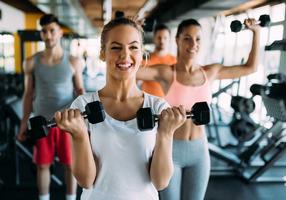 Gruppe junger Leute beim Hanteltraining im Fitnessstudio