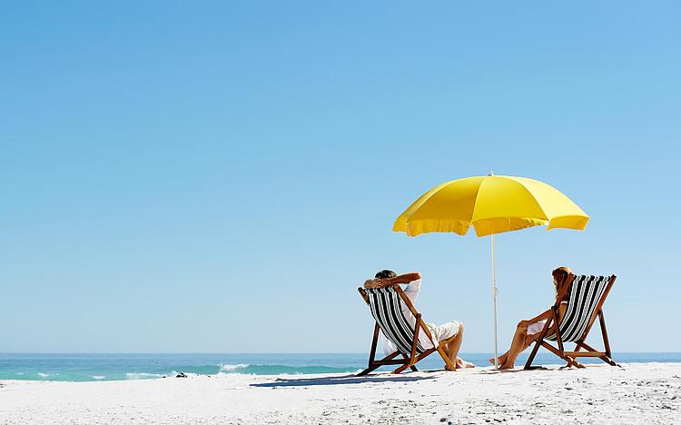 Liegestühle und Sonnenschirm am Strand