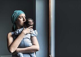 Frau mit Baby auf dem Arm, die Frau schaut traurig aus.
