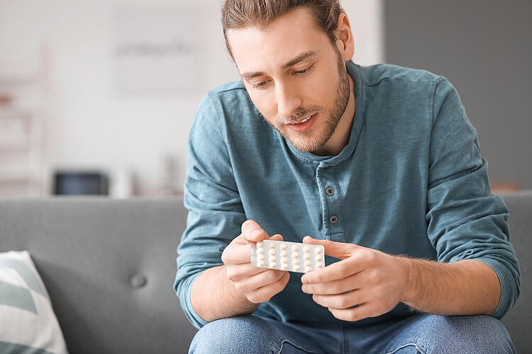 Mann hält Tabletten in einer Blisterpackung in der Hand