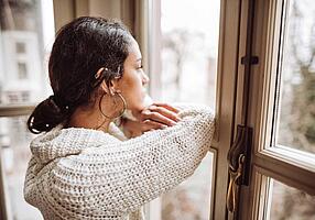 Frau schaut traurig aus dem Fenster