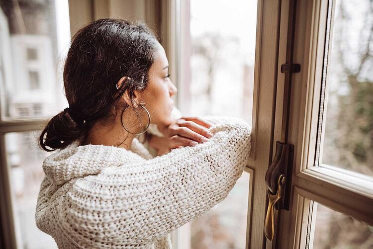 Frau schaut traurig aus dem Fenster