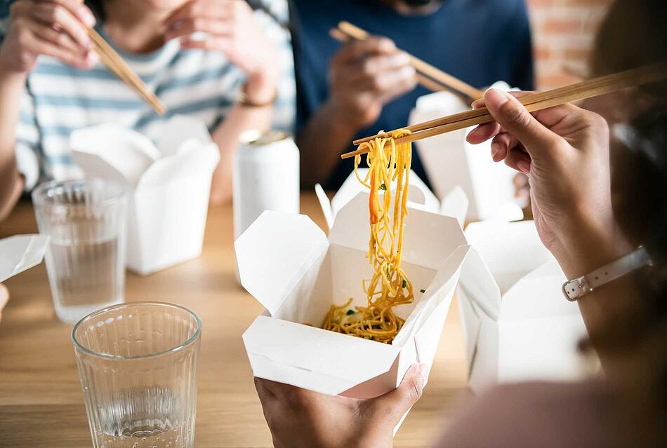 Freunde essen chinesische Nudeln mit Stäbchen