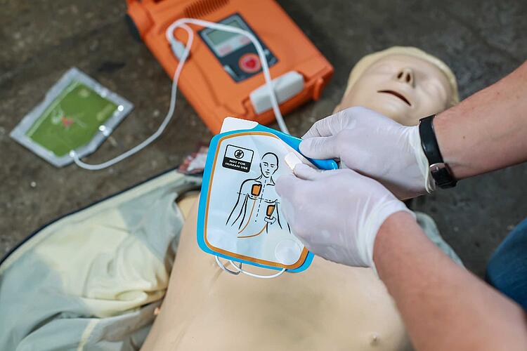 Erste Hilfe Übung mit Defibrillator an einer Puppe