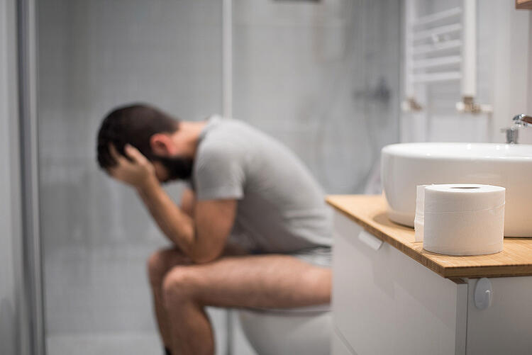 Mann sitzt auf der Toilette